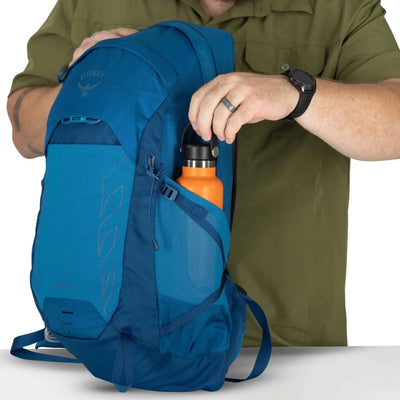 Person placing a water bottle into the side pocket of the Osprey Talon 22 Extended Fit - Men backpack.