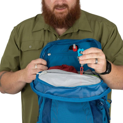 A user showcasing the interior of the Osprey Talon 22 Extended Fit - Men backpack, displaying pockets and storage options.
