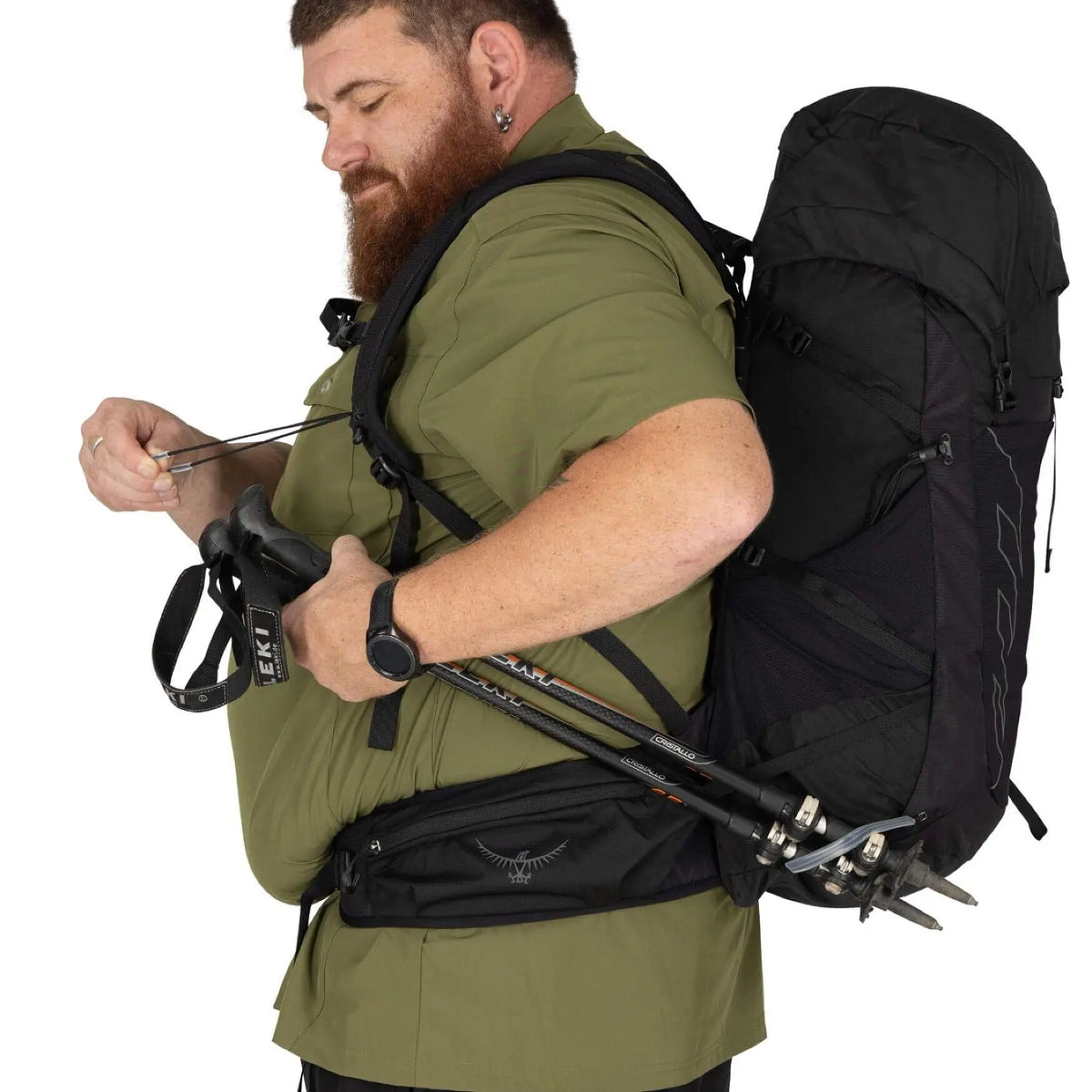 Man wearing Osprey Talon 33 Extended Fit daypack, demonstrating comfortable fit with trekking poles and outdoor gear.