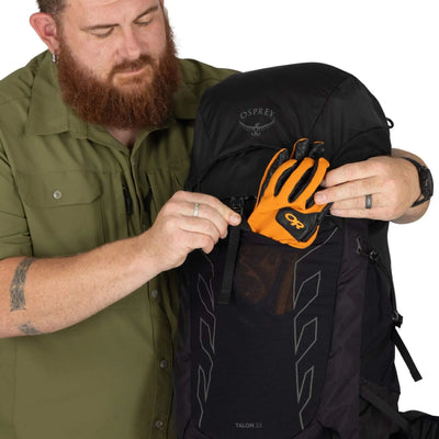 Man adjusts Osprey Talon 33 Extended Fit men's travel daypack, showcasing ergonomic design and versatile storage options.