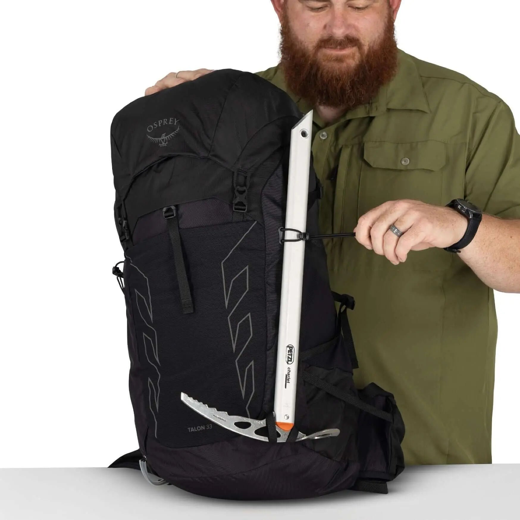 Man holding Osprey Talon 33 Extended Fit men's travel daypack with hiking gear attachment.