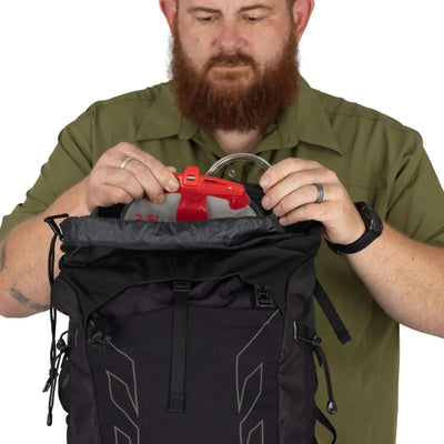 Man packing Osprey Talon 33 Extended Fit daypack for travel or hiking excursion.