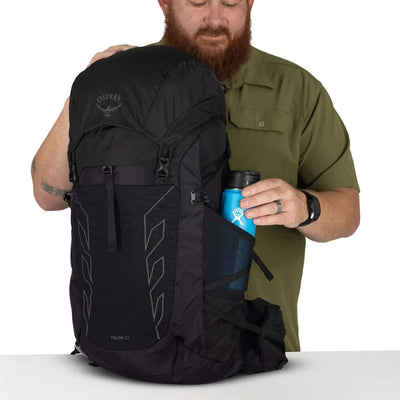 Man with Osprey Talon 33 Extended Fit men's travel daypack, showing bottle pocket