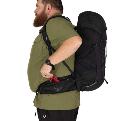 Man wearing Osprey Talon 33 Extended Fit daypack, showcasing side pocket access and ergonomic design for broader body types.