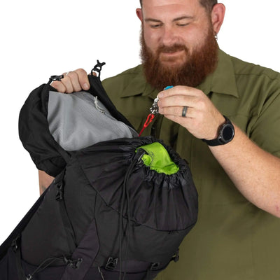 Man examining the Osprey Talon 33 Extended Fit, a versatile men's travel daypack, with focus on top-loading feature and spacious interior.