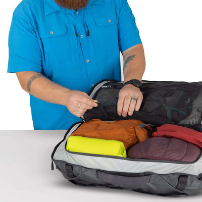 Man packing the Transporter Squffel 44 with colorful gear, showcasing its functional design and rugged durability.