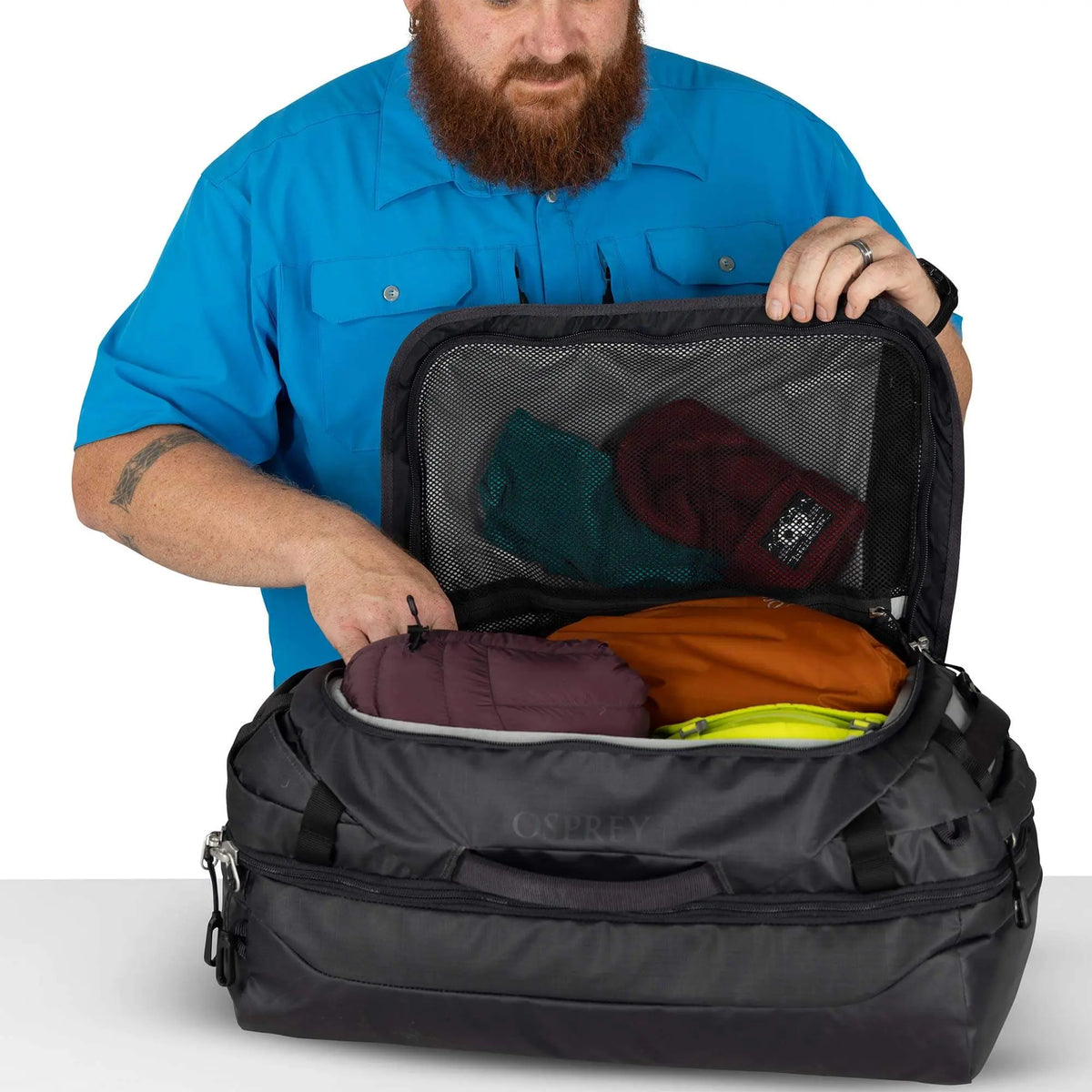 Man unpacking the Osprey Transporter Squffel 44 bag, showcasing its spacious interior and organized packing.