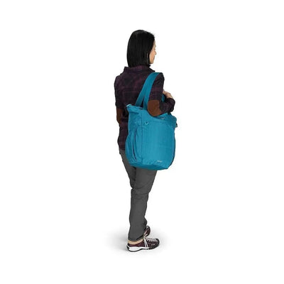 Person carrying Osprey Poco Changing Tote in blue with removable mat and insulated bottle pockets for seamless parenting on the go.