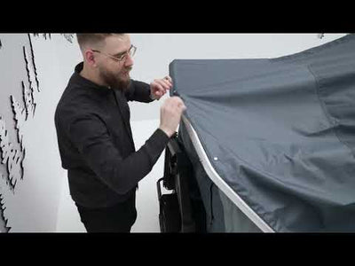 Man setting up the Thule Thule Outset - 3-person towbar-mounted car tent for outdoor camping.