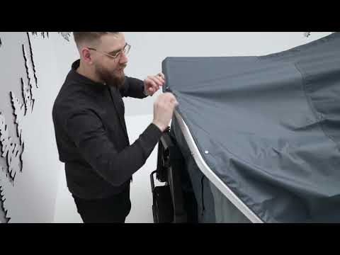 Man setting up the Thule Thule Outset - 3-person towbar-mounted car tent for outdoor camping.