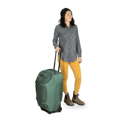 Woman pulling Osprey Sojourn Shuttle Wheeled Duffel 25"/60L with 90 mm wheels and AirScape back panel for comfortable travel.