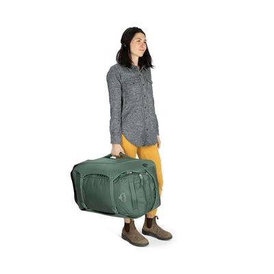 Person carrying Osprey Sojourn Shuttle Wheeled Duffel 25"/60L, featuring oversized wheels and StraightJacket compression. Ideal for travel.