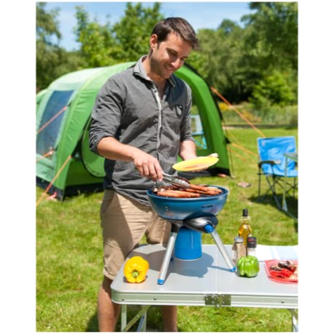 Man using Campingaz C206 Cartridge Gas Canister for outdoor cooking near a tent.