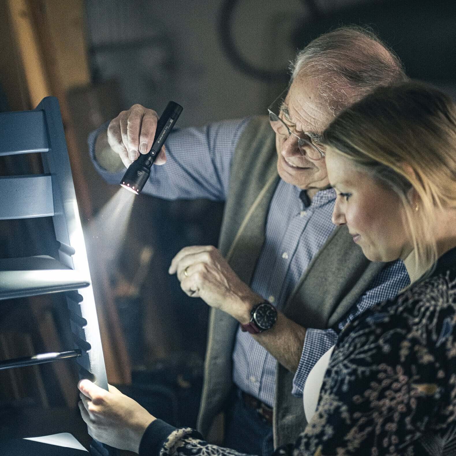 P6R flashlight used by a man and woman inspecting a project in a dimly lit workshop.