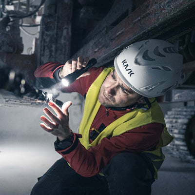 A person using the P7R flashlight for close-up work in a dark environment, wearing protective gear.