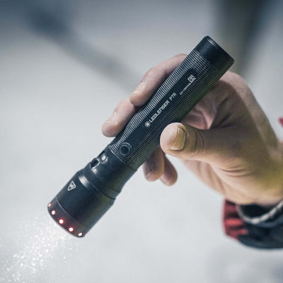 Hand holding the P7R flashlight showcasing its focus and light modes in action.